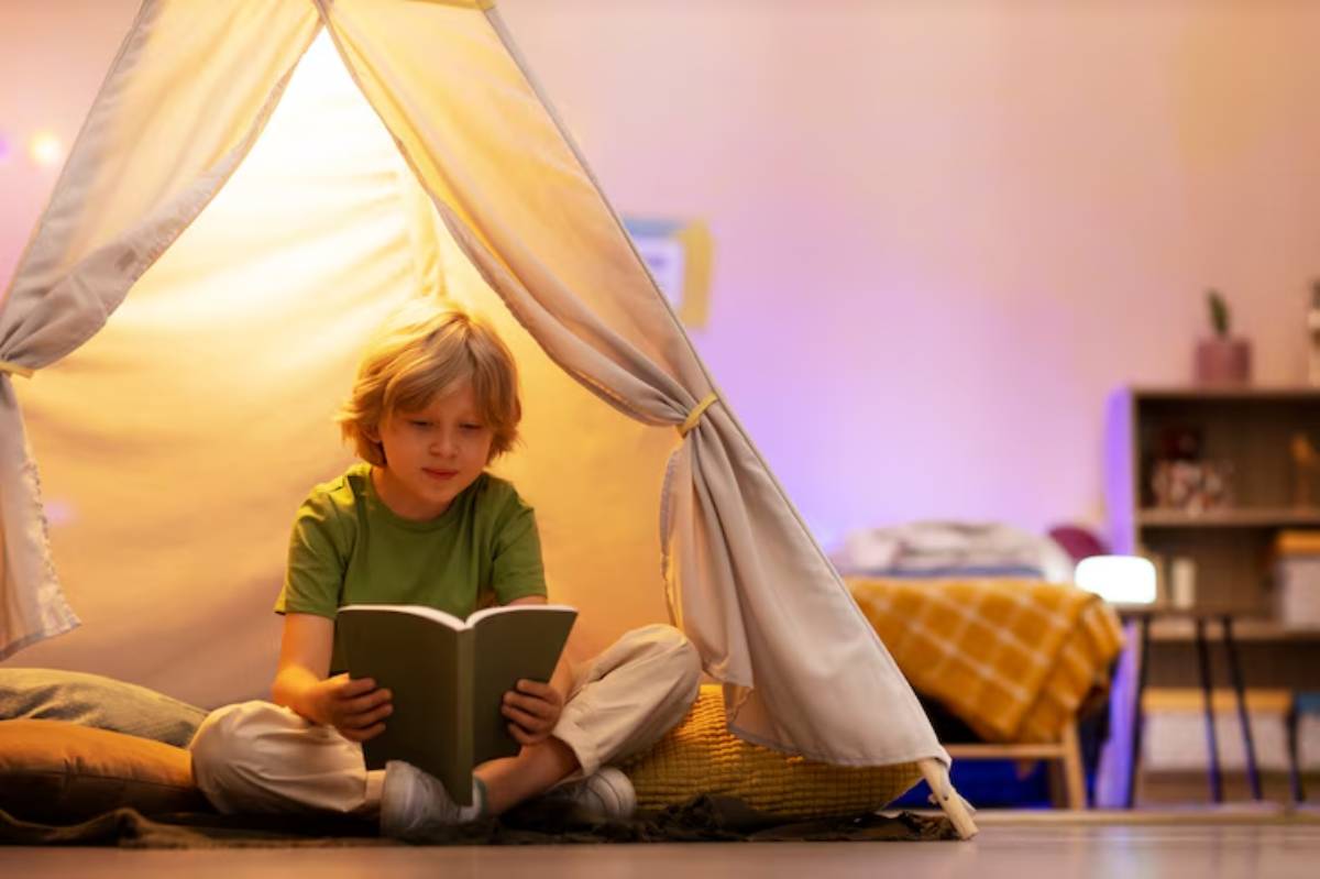 A child sits cross-legged inside a cozy tent, immersed in reading a book, surrounded by soft pillows and warm lighting.