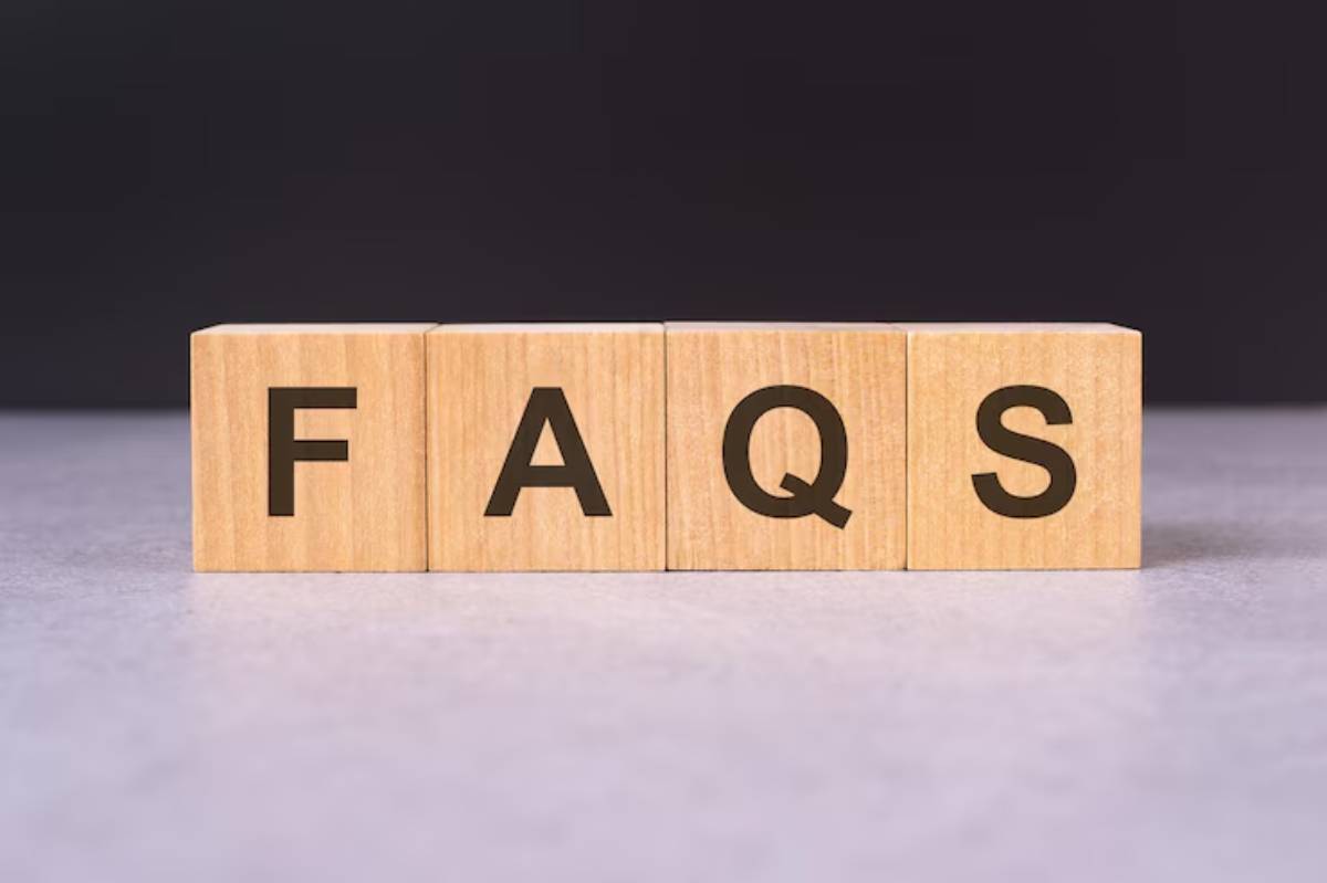 Wooden blocks displaying the letters  on a gray surface, against a dark background, representing frequently asked questions.