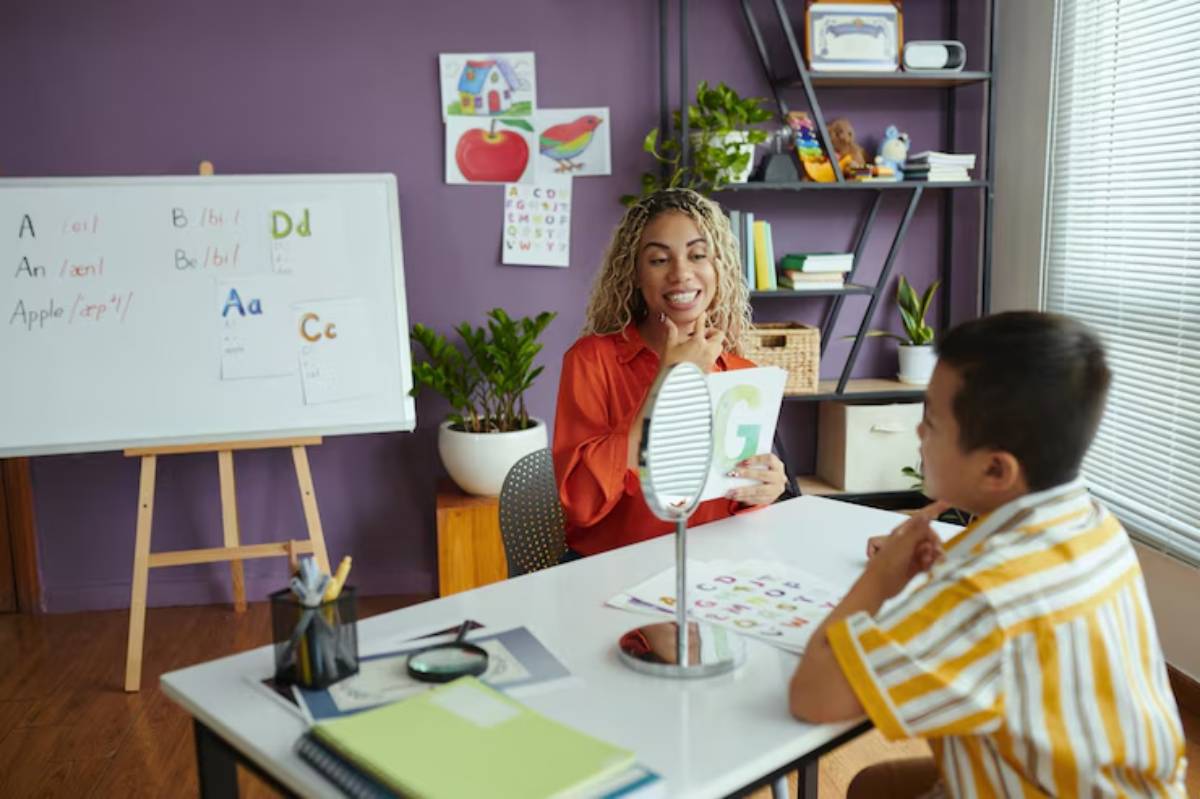 A classroom scene with a teacher holding a letter card, teaching a young student, surrounded by educational materials and colorful drawings.