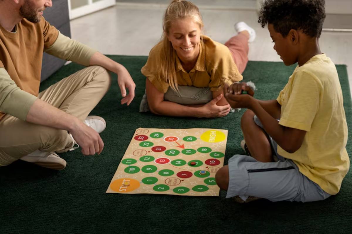 A group of children and an adult play a colorful board game on a green carpet, engaging in friendly competition and cooperation.