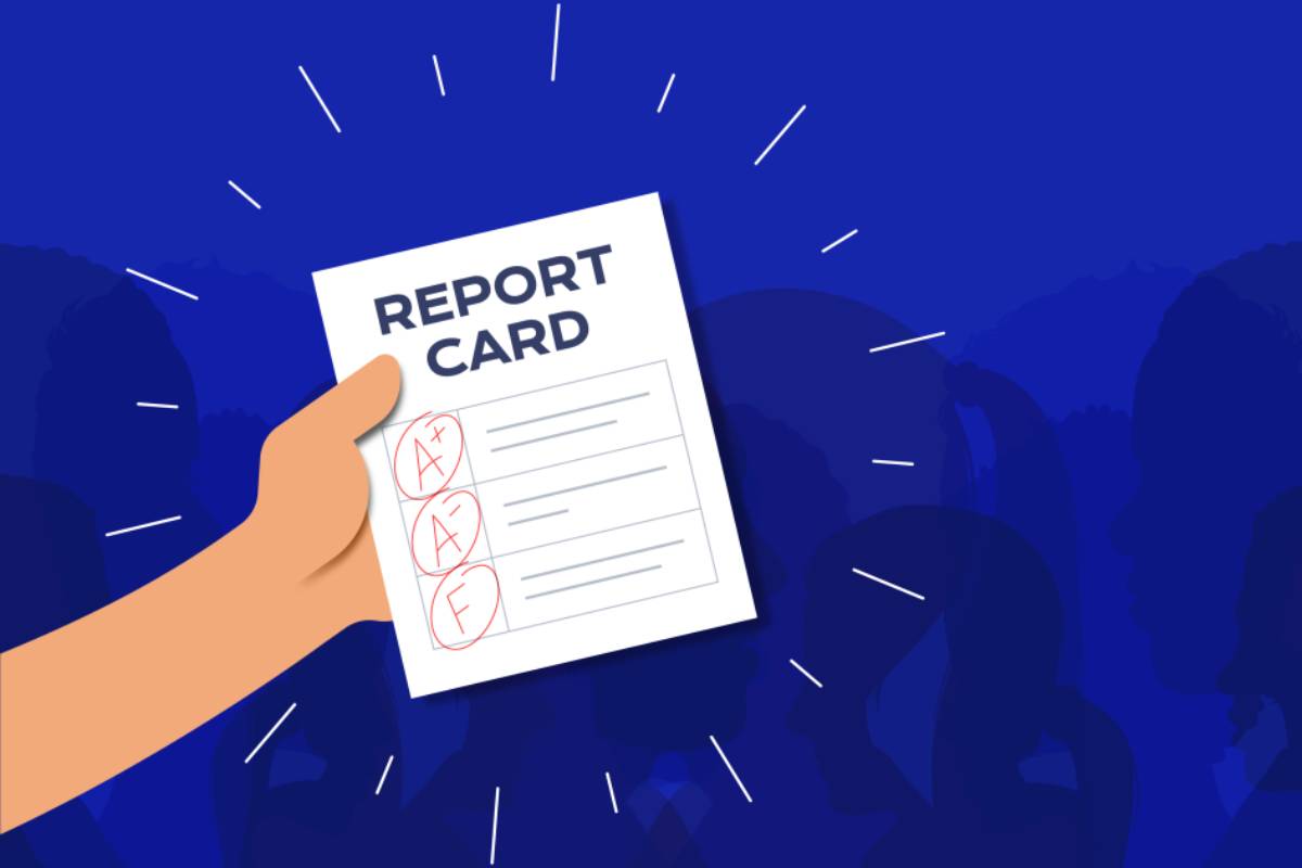 A hand holding a report card displaying grades A+, A, and F, with an audience silhouette in the background.