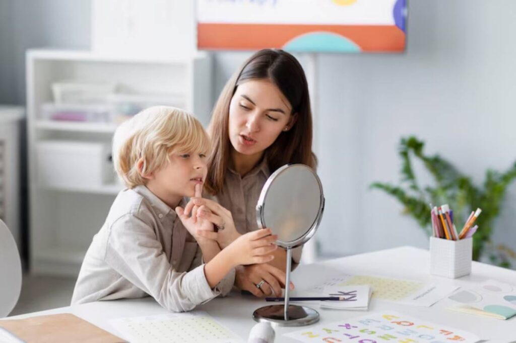 A child and an adult are engaged in a reflective moment in front of a table covered with colorful papers and a mirror.